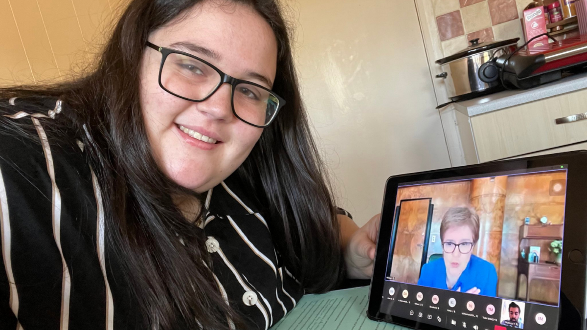 Ilse Cutherbertson MSYP is holding a tablet showing a videochat with the First Minister, Nicola Sturgeoon.