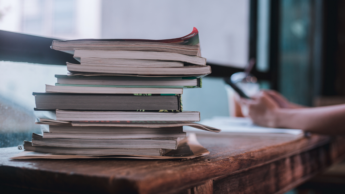 Image of a stack of books and someone studying next to them