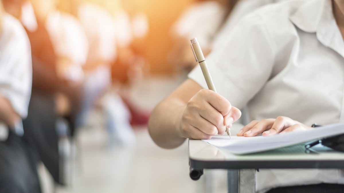 Image of a person holding a pen writing in a book at a desk