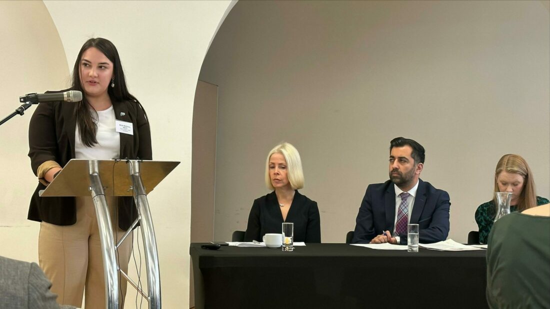 SYP Chair Mollie McGoran standing at a lectern speaking at the First Minister's Anti-Poverty Summit in Edinburgh on 3rd May 2023