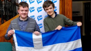 Shetland MSYPs holding up a Shetland flag against a SYP pop-up banner