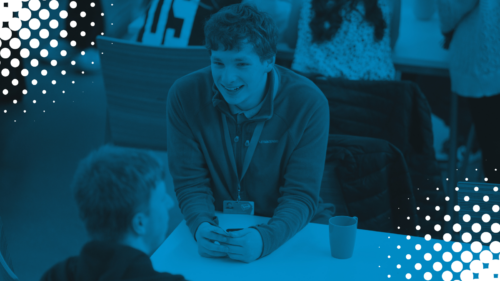 Image from the back of an auditorium with MSYPs facing the front with their hands in the air. Blue tint overlaid with white polka dots in corners.