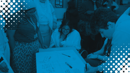 Image of MSYPs taking part in a group activity, looking at and writing on flip chart paper. Blue tint overlaid with white polka dots in corners.