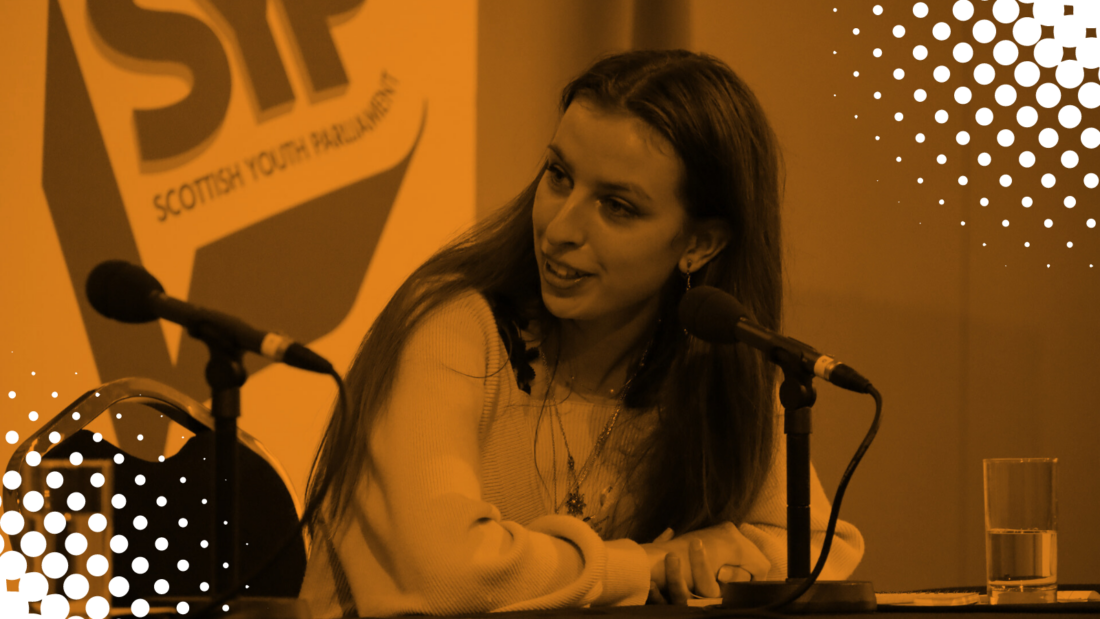 Image of an MSYP sitting at a table taking part in a panel discussion at an event. Orange tint overlaid with white polka dots in corners.