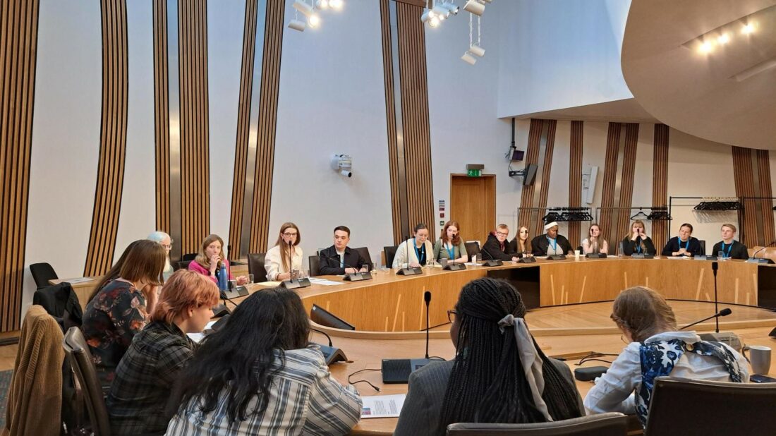 MSYPs sitting round a table in a committee room during SYP82 at The Scottish Parliament