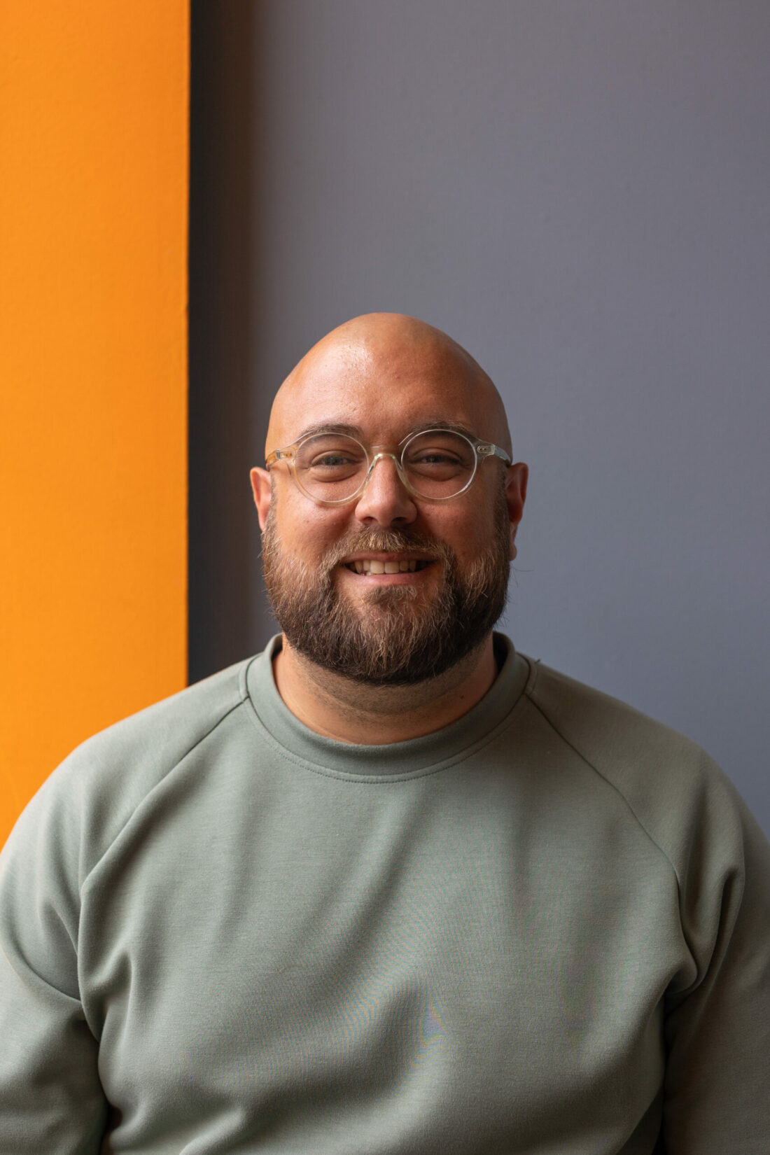 CEO Jamie Dunlop poses in a headshot, smilling and wearing glasses and a green t-shirt.
